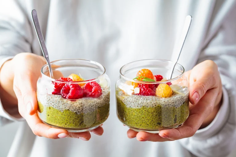 Two glasses of matcha chia seed pudding topped with raspberries and golden berries – healthy quick breakfast inspiration from Honesta