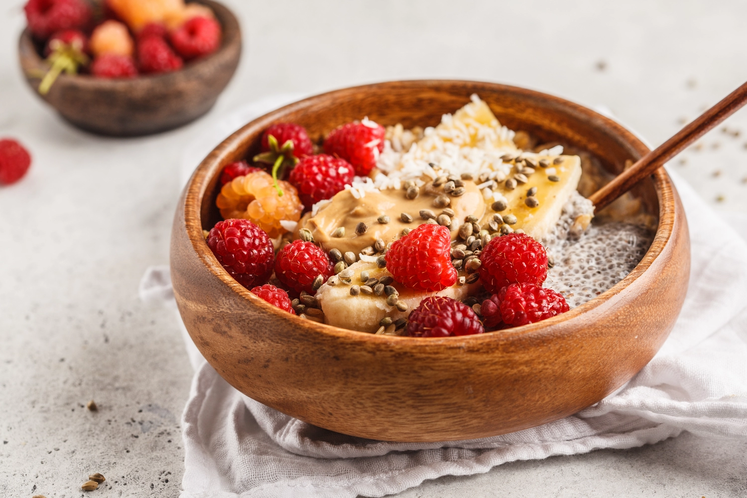 Wooden bowl of chia seed pudding topped with fresh strawberries, banana and seeds – nutrient dense breakfast for gut health by Honesta