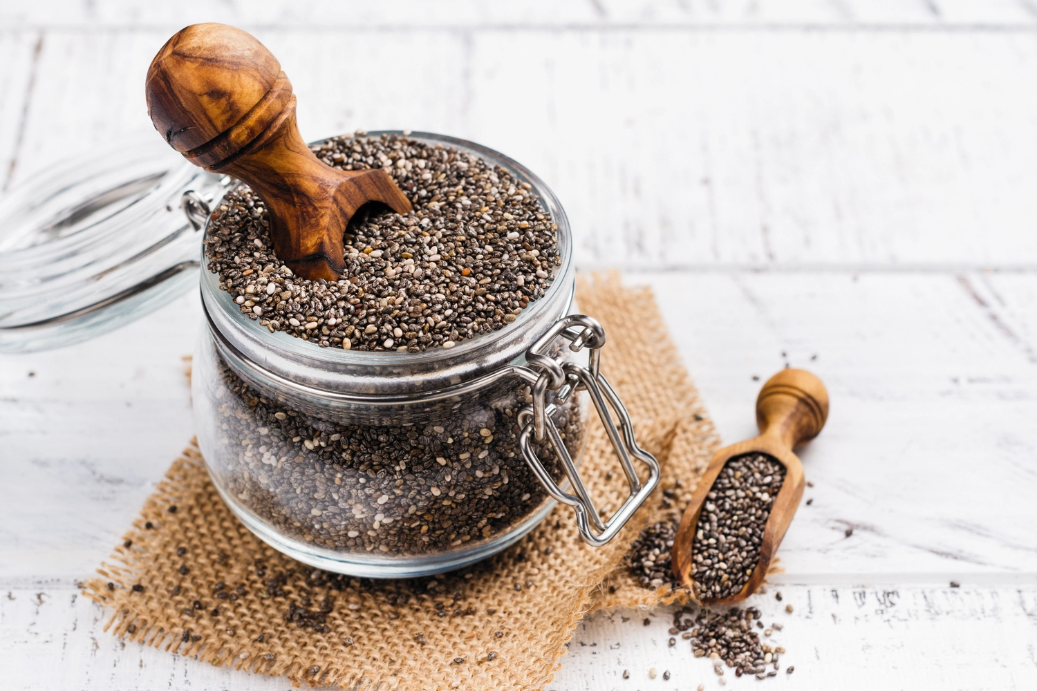 Glass jar of raw chia seeds with wooden scoop – high fiber superfood for healthy breakfast and gut health