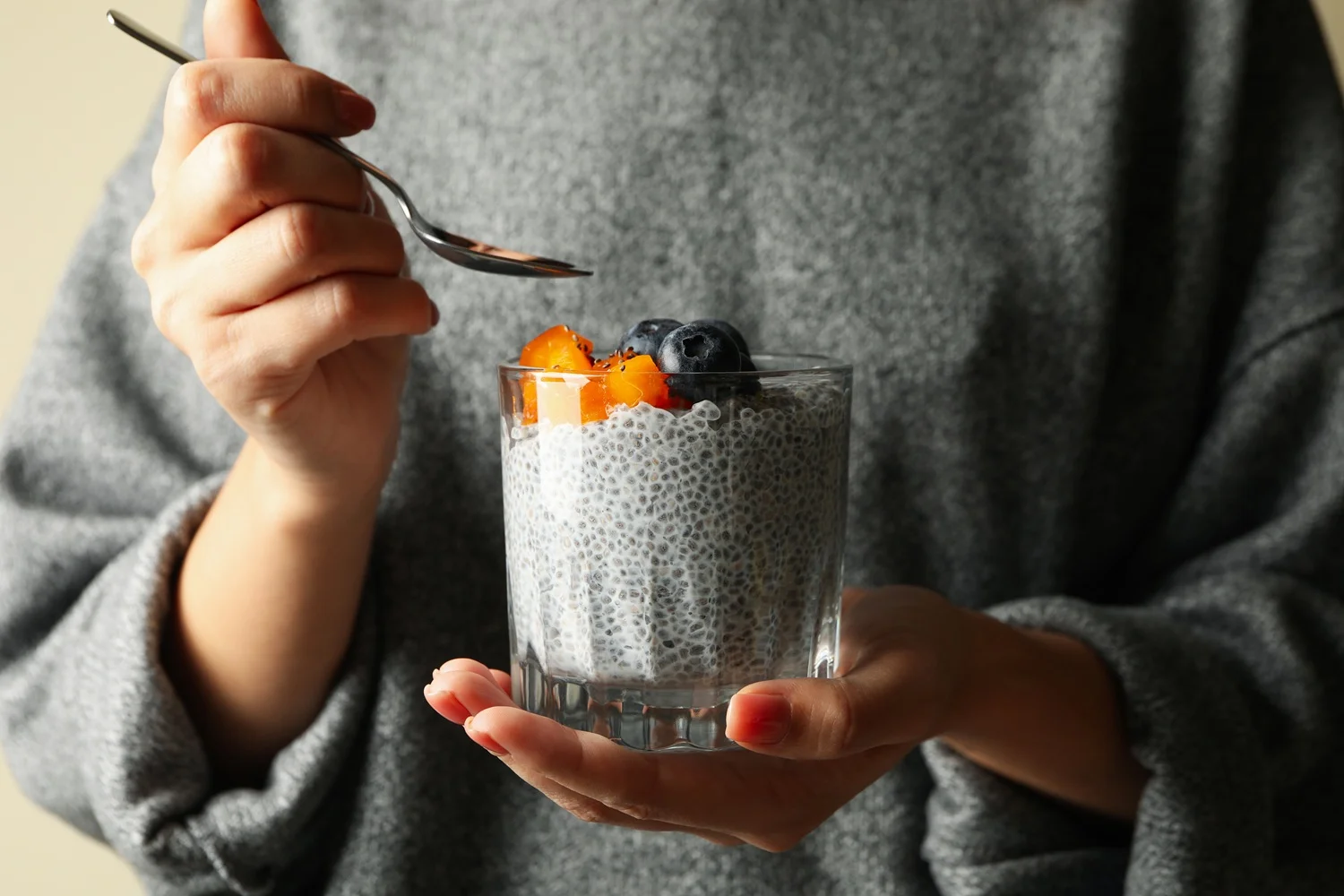 Woman eating chia pudding showing how to consume chia seeds with fruit.